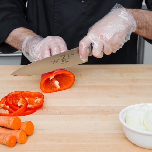 Chef con guantes desechables cortando verduras